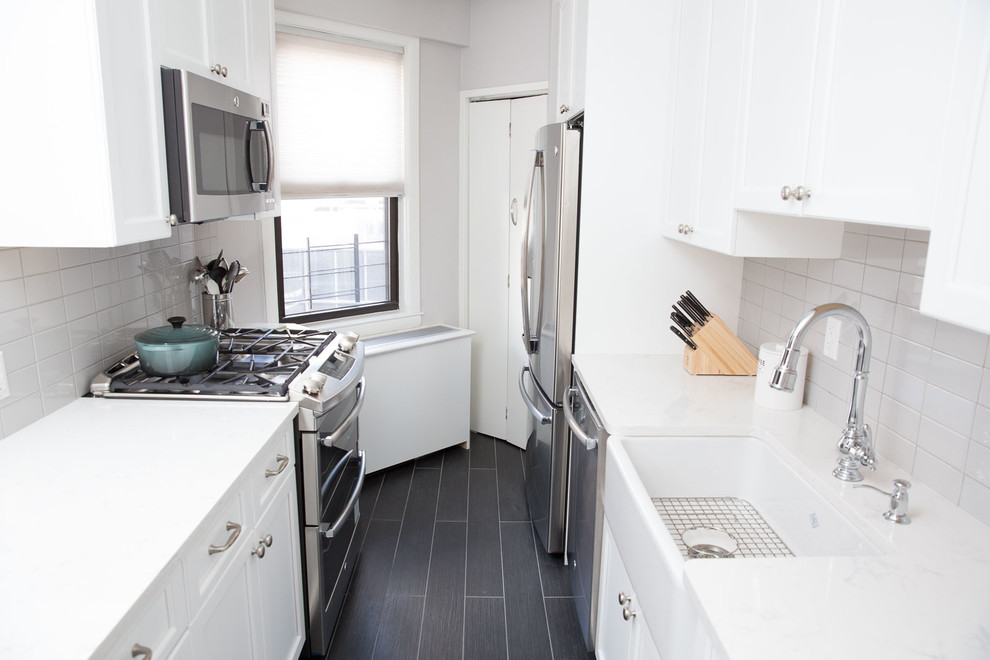 Inspiration for a small traditional galley separate kitchen in New York with a farmhouse sink, shaker cabinets, white cabinets, white splashback, ceramic splashback, stainless steel appliances, porcelain floors and no island.