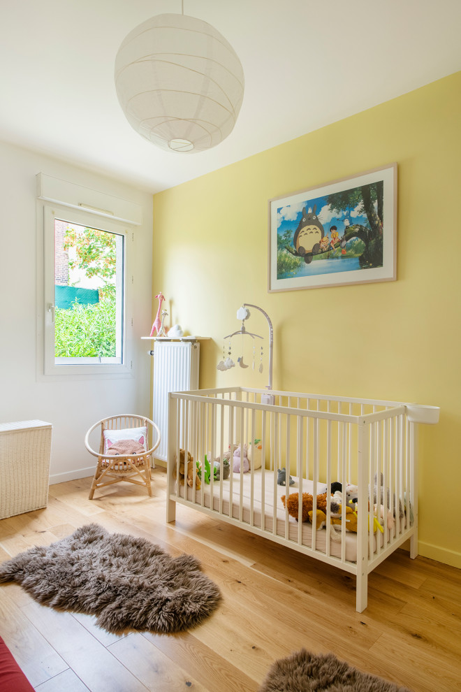 Foto de habitación de bebé neutra escandinava de tamaño medio con paredes amarillas, suelo de madera clara y suelo beige