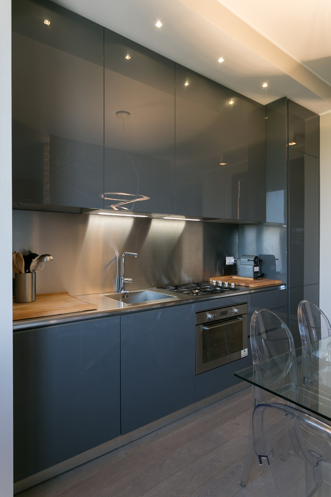 Design ideas for a mid-sized contemporary single-wall eat-in kitchen in Milan with an integrated sink, flat-panel cabinets, grey cabinets, metallic splashback, metal splashback, stainless steel appliances and no island.