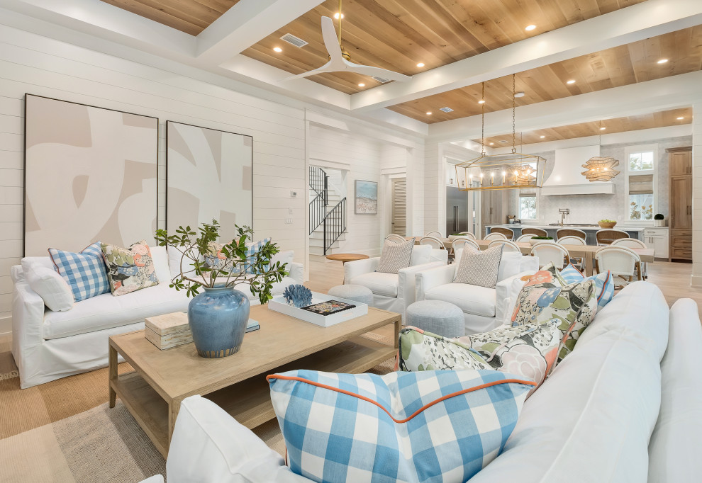 Large beach style open concept living room in Miami with white walls, light hardwood floors, a standard fireplace, a brick fireplace surround, a wall-mounted tv, wood and planked wall panelling.