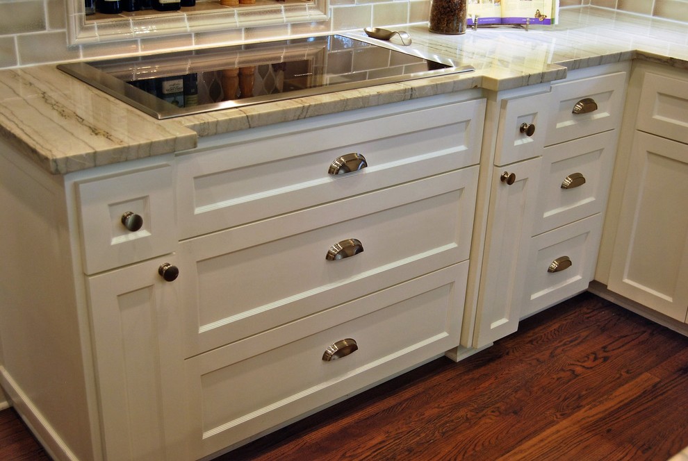 Example of a mid-sized transitional u-shaped light wood floor kitchen design in Austin with a farmhouse sink, shaker cabinets, white cabinets, quartzite countertops, beige backsplash, porcelain backsplash, stainless steel appliances and an island