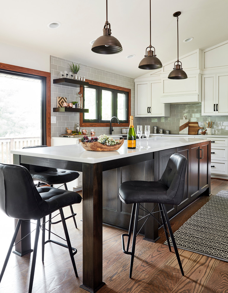 Design ideas for a mid-sized country u-shaped eat-in kitchen in Other with a farmhouse sink, recessed-panel cabinets, white cabinets, glass benchtops, grey splashback, glass tile splashback, panelled appliances, medium hardwood floors, with island, brown floor and white benchtop.