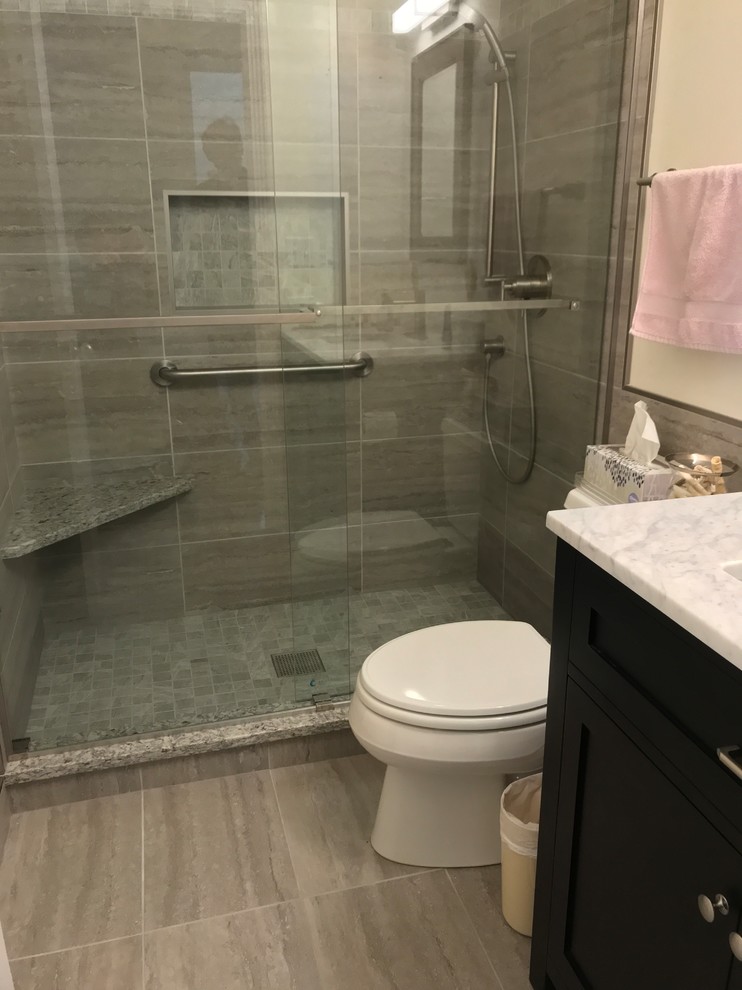 This is an example of a small transitional 3/4 bathroom in Chicago with shaker cabinets, dark wood cabinets, an alcove shower, a two-piece toilet, beige tile, porcelain tile, beige walls, porcelain floors, an undermount sink, marble benchtops, beige floor, a sliding shower screen and grey benchtops.