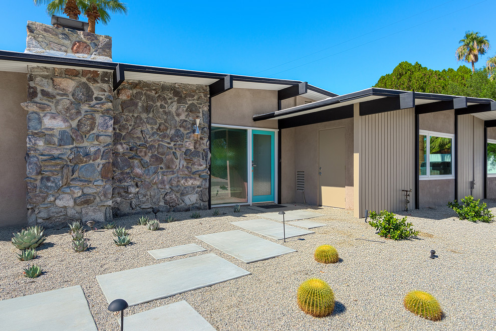 Photo of a midcentury exterior in Other with stone veneer and a gable roof.