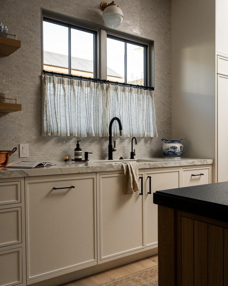 Example of a transitional light wood floor kitchen design in Orange County with marble backsplash and an island