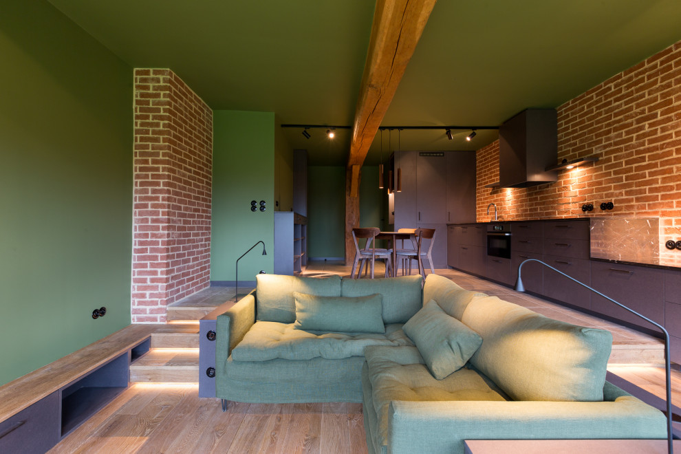 Imagen de salón abierto industrial de tamaño medio con paredes verdes, suelo marrón y ladrillo