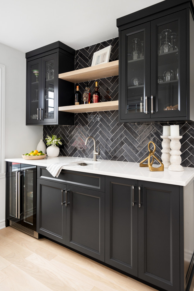 Inspiration for a large transitional single-wall home bar in Montreal with an undermount sink, beaded inset cabinets, white cabinets, quartz benchtops, grey splashback, ceramic splashback, light hardwood floors, brown floor and white benchtop.