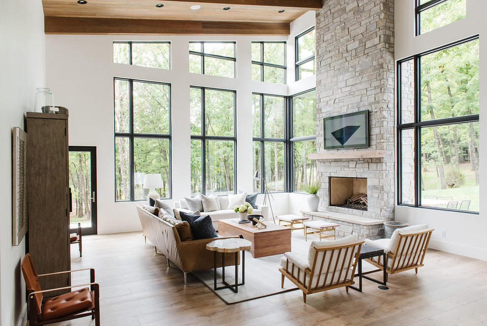 Inspiration for a large country open concept living room in Salt Lake City with white walls, light hardwood floors, a standard fireplace, a stone fireplace surround and a concealed tv.