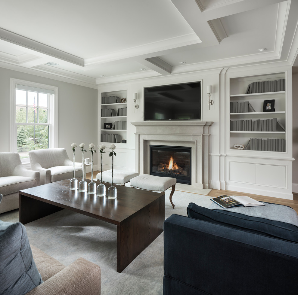 This is an example of a mid-sized transitional open concept living room in Minneapolis with grey walls, light hardwood floors, a standard fireplace, a stone fireplace surround, a wall-mounted tv and brown floor.