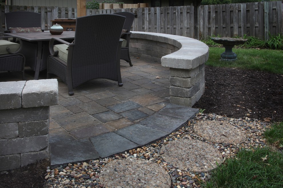 This is an example of a large traditional backyard patio in Omaha with a fire feature, concrete pavers and no cover.