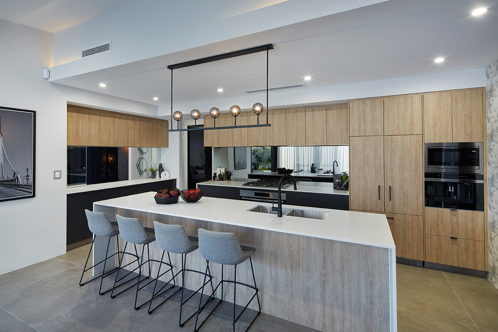 Photo of a contemporary l-shaped kitchen in Perth with a double-bowl sink, flat-panel cabinets, light wood cabinets, mirror splashback, black appliances, with island, beige floor and white benchtop.