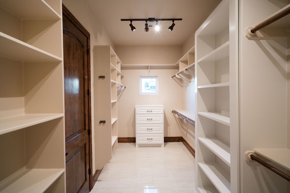 Photo of a large traditional gender-neutral walk-in wardrobe in Austin with raised-panel cabinets, white cabinets, marble floors and beige floor.