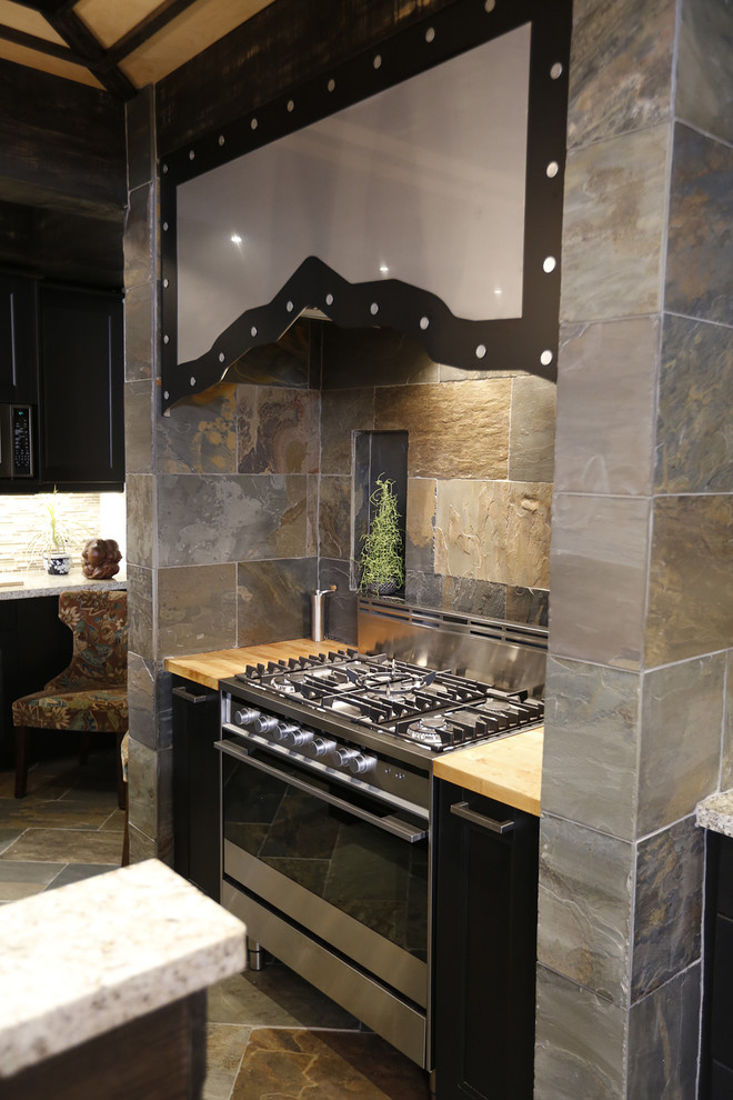 Example of a large mountain style galley slate floor open concept kitchen design in Toronto with an undermount sink, shaker cabinets, dark wood cabinets, solid surface countertops, multicolored backsplash, stone tile backsplash, stainless steel appliances and an island