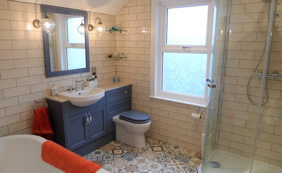 Photo of a mid-sized traditional kids bathroom in Other with beaded inset cabinets, blue cabinets, a freestanding tub, a corner shower, ceramic tile, ceramic floors, solid surface benchtops, a hinged shower door and grey benchtops.