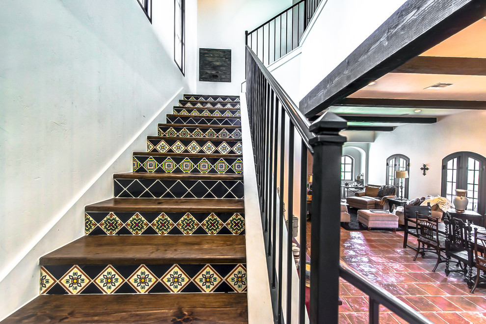 Large wood staircase in Austin with tile risers and metal railing.