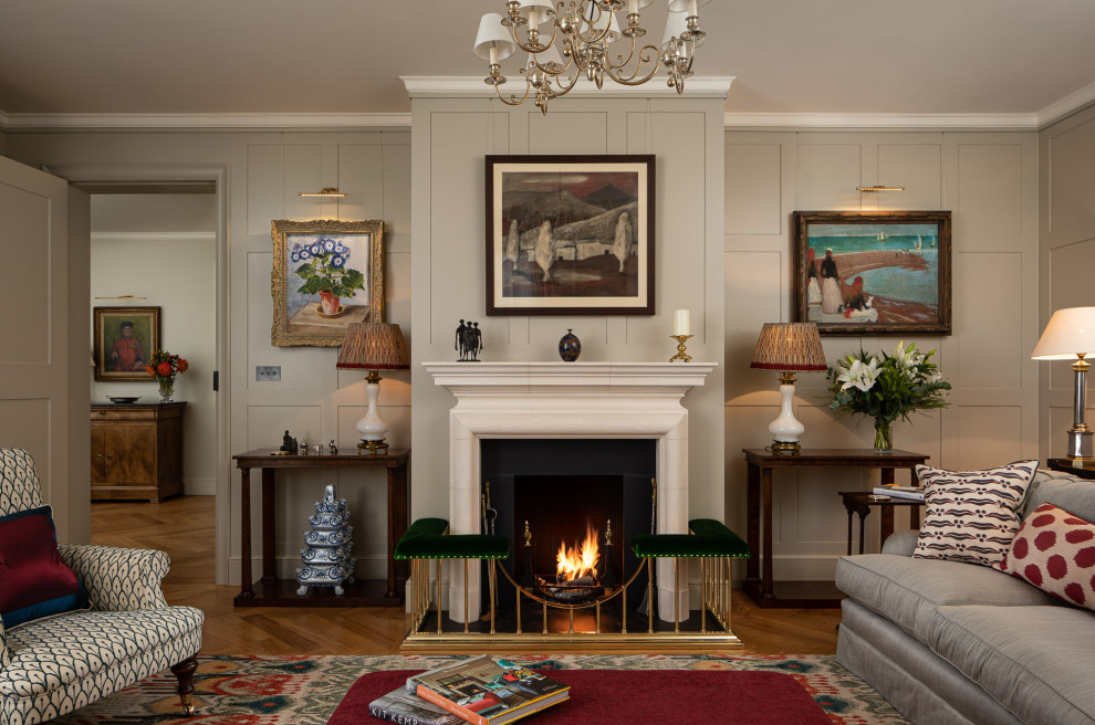 Photo of a large traditional enclosed living room in London with medium hardwood floors, a standard fireplace, no tv, panelled walls, grey walls and brown floor.