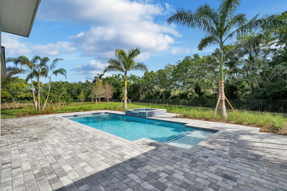 Design ideas for a mid-sized traditional backyard rectangular lap pool in Miami with a hot tub and brick pavers.