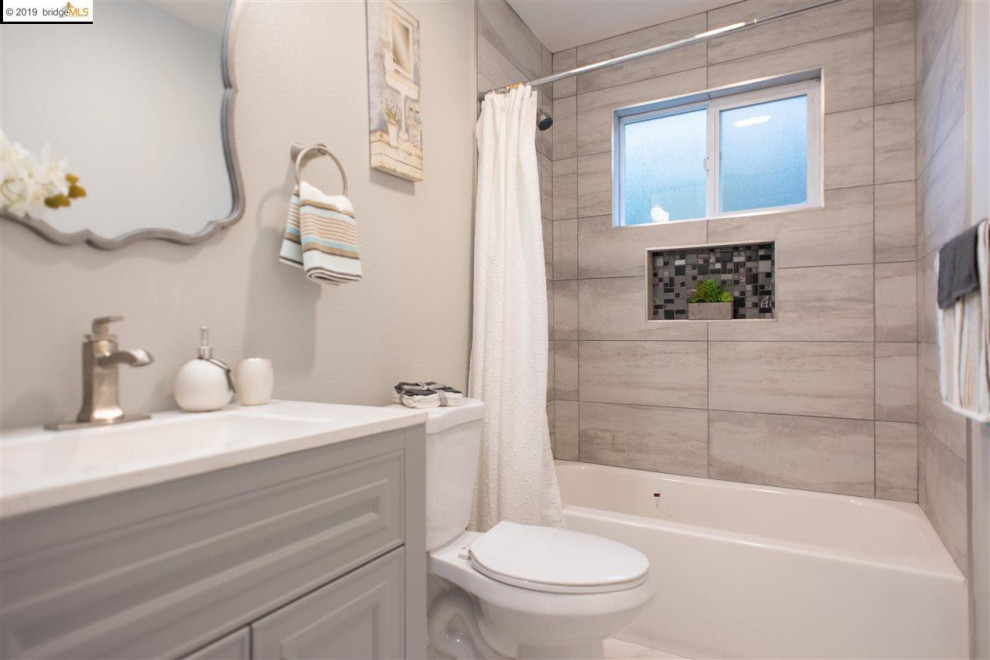 Inspiration för mellanstora moderna vitt en-suite badrum, med skåp i shakerstil, grå skåp, ett badkar i en alkov, en dusch/badkar-kombination, en toalettstol med separat cisternkåpa, grå kakel, keramikplattor, vita väggar, ett integrerad handfat och dusch med duschdraperi