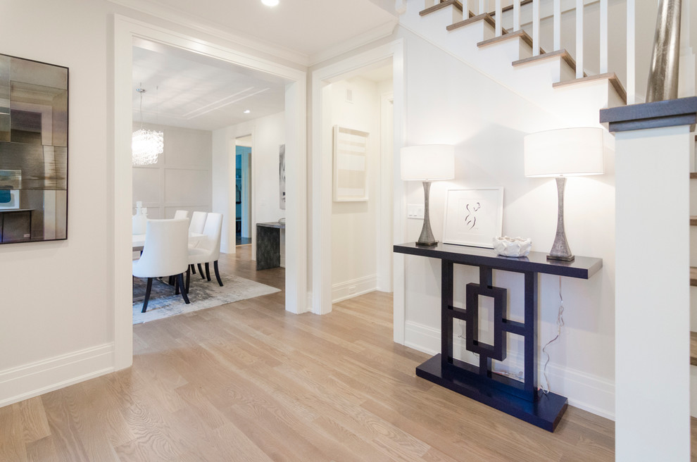 Photo of a large transitional front door in New York with white walls and light hardwood floors.