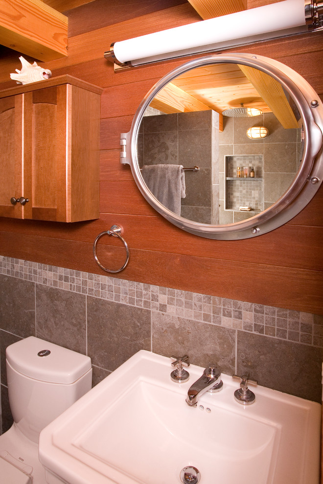 This is an example of a small eclectic 3/4 bathroom in Seattle with recessed-panel cabinets, medium wood cabinets, an open shower, a one-piece toilet, gray tile, stone tile, a pedestal sink, multi-coloured walls and limestone floors.