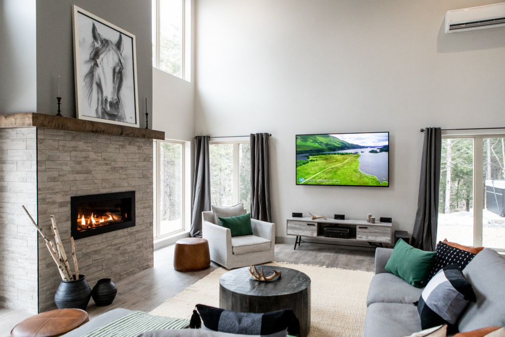 Expansive modern open concept living room in Other with laminate floors, a standard fireplace, a stone fireplace surround and a wall-mounted tv.