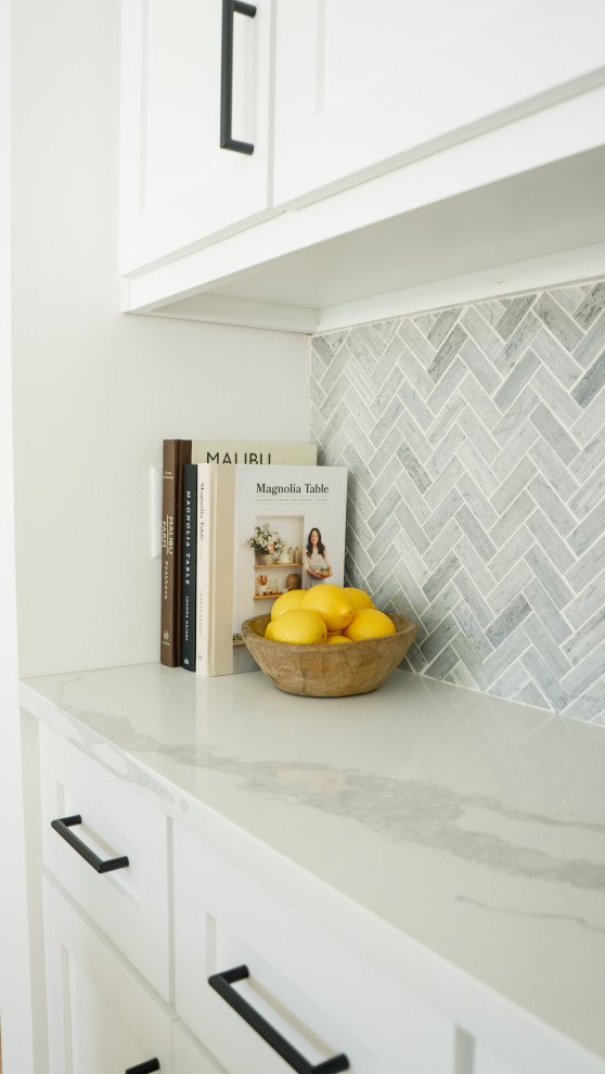 Example of a transitional kitchen design in Austin with a farmhouse sink, shaker cabinets, white cabinets, quartz countertops, gray backsplash and stone tile backsplash