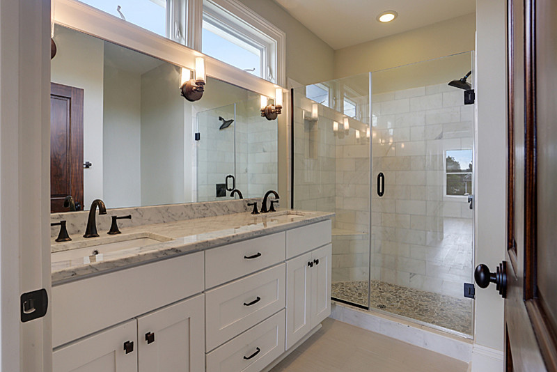 This is an example of a contemporary bathroom in New Orleans with an integrated sink, flat-panel cabinets, white cabinets, marble benchtops, an alcove shower, a one-piece toilet, brown tile, pebble tile and ceramic floors.