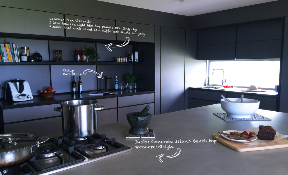 This is an example of an expansive industrial u-shaped eat-in kitchen in Sydney with a drop-in sink, concrete benchtops, metallic splashback, stainless steel appliances, light hardwood floors and with island.