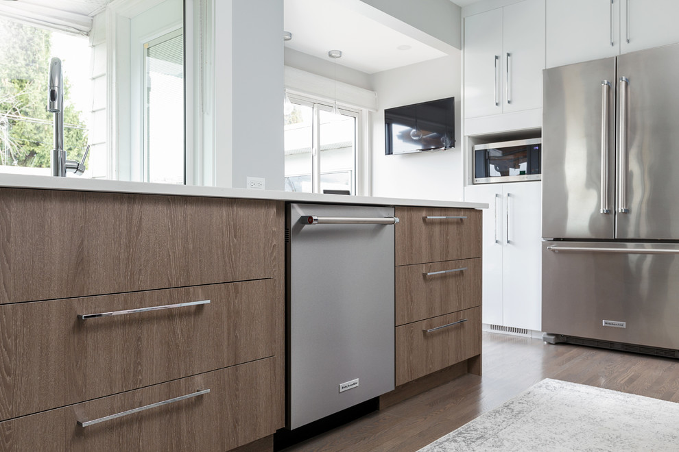 Mid-sized contemporary galley eat-in kitchen in Vancouver with a double-bowl sink, flat-panel cabinets, white cabinets, quartz benchtops, grey splashback, glass sheet splashback, stainless steel appliances, light hardwood floors, a peninsula, grey floor and white benchtop.