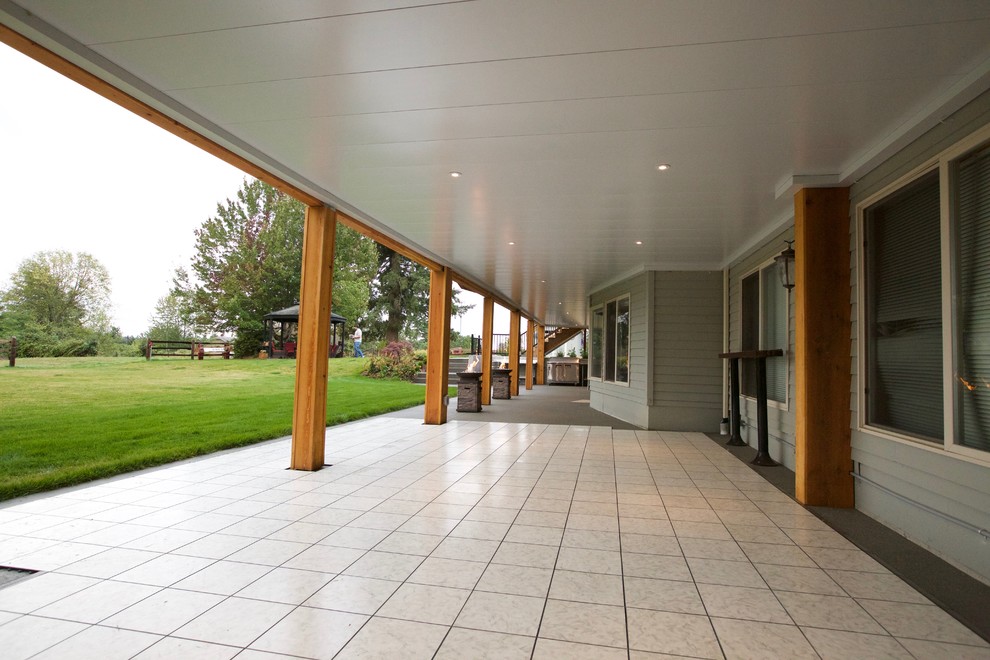 Large mountain style backyard outdoor kitchen deck photo in Seattle with a roof extension