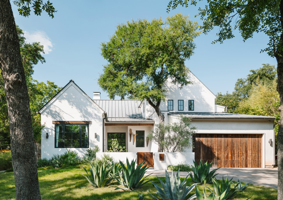 Photo of a contemporary two-storey white house exterior in Austin with a gable roof and a metal roof.