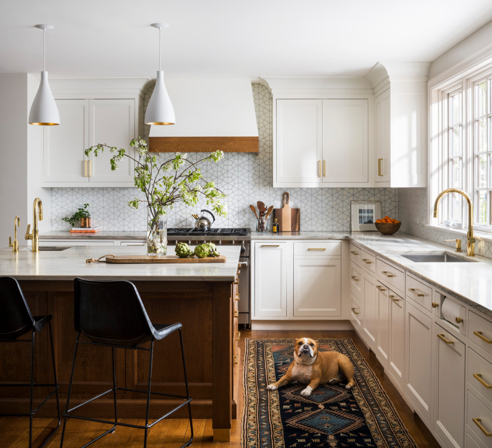 Photo of a large traditional u-shaped eat-in kitchen in New York with a single-bowl sink, shaker cabinets, white cabinets, quartzite benchtops, white splashback, ceramic splashback, stainless steel appliances, medium hardwood floors, with island, brown floor and white benchtop.
