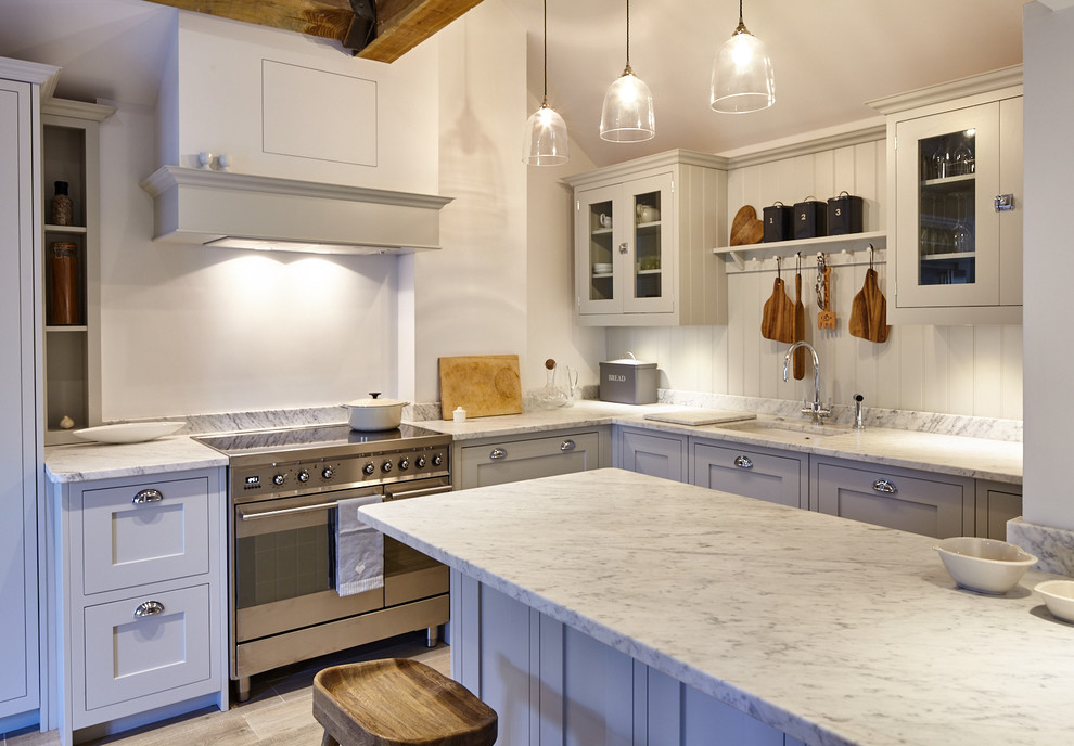 Photo of a mid-sized contemporary l-shaped eat-in kitchen in Wiltshire with a single-bowl sink, shaker cabinets, grey cabinets, marble benchtops, grey splashback, stone tile splashback, panelled appliances, porcelain floors and a peninsula.