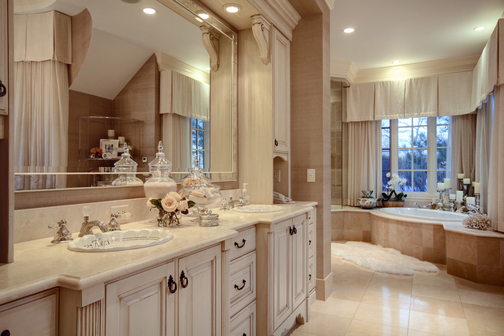 Inspiration for an expansive mediterranean master bathroom in Denver with a drop-in sink, beige cabinets, marble benchtops, a drop-in tub, beige tile, stone tile, beige walls, marble floors and raised-panel cabinets.