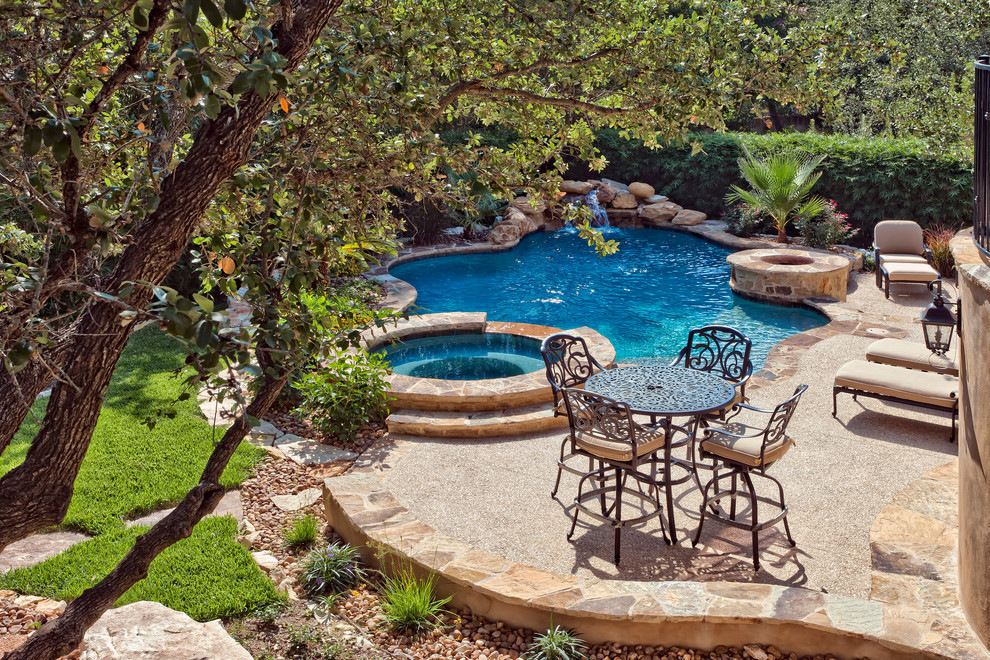 Photo of a mid-sized traditional backyard custom-shaped pool in Austin with a hot tub.