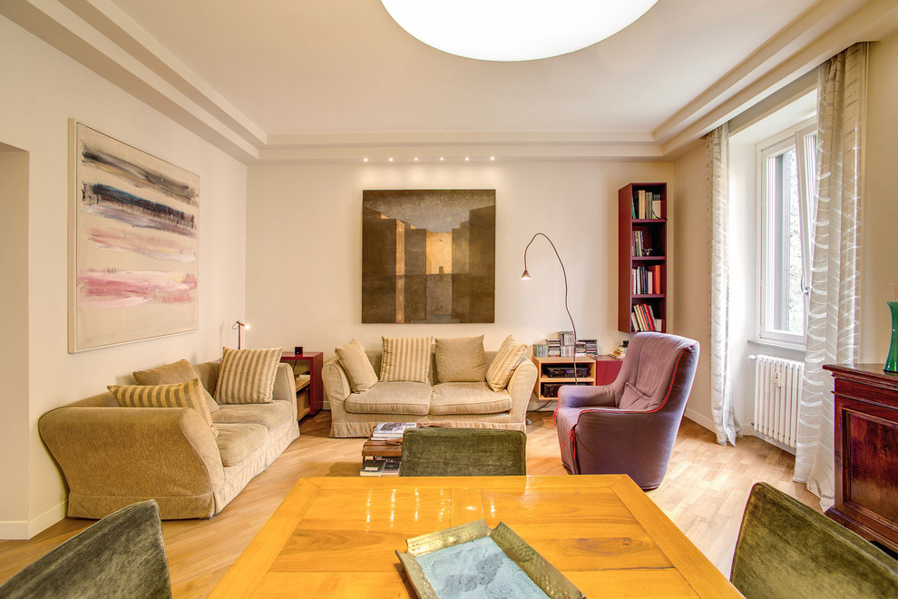 This is an example of a large eclectic open concept living room in Rome with white walls and light hardwood floors.