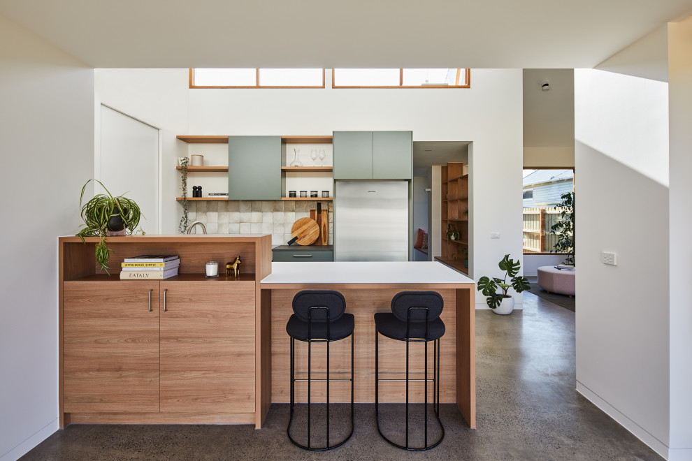 Contemporary galley kitchen in Melbourne with flat-panel cabinets, grey cabinets, white splashback, stainless steel appliances, concrete floors, a peninsula, grey floor and white benchtop.