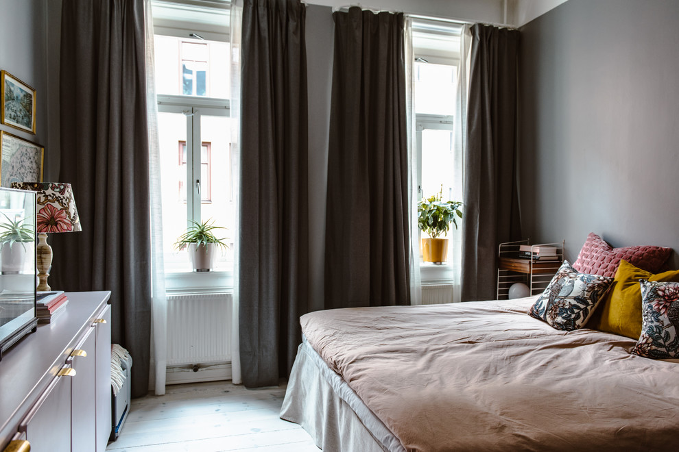 Mid-sized eclectic bedroom in Stockholm with light hardwood floors, grey walls and white floor.
