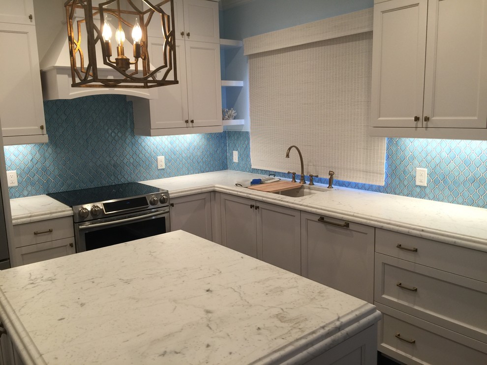 Inspiration for a mid-sized coastal l-shaped dark wood floor and brown floor kitchen pantry remodel with an undermount sink, shaker cabinets, white cabinets, soapstone countertops, blue backsplash, ceramic backsplash, stainless steel appliances and an island