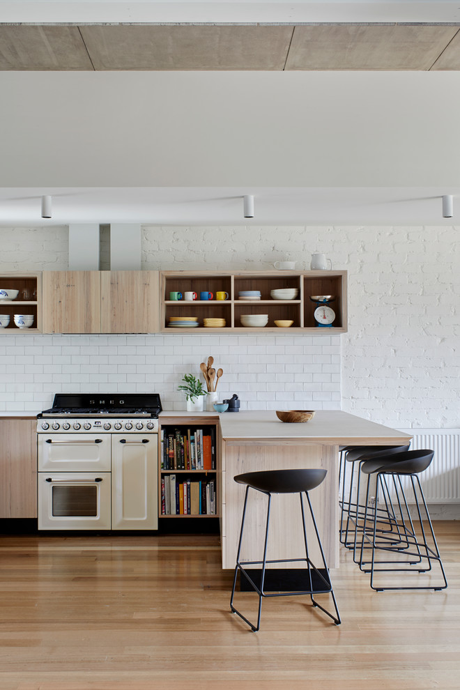 Inspiration for a mid-sized contemporary kitchen in Melbourne with a double-bowl sink, flat-panel cabinets, light wood cabinets, quartz benchtops, white splashback, porcelain splashback, white appliances, with island, beige benchtop, light hardwood floors and beige floor.
