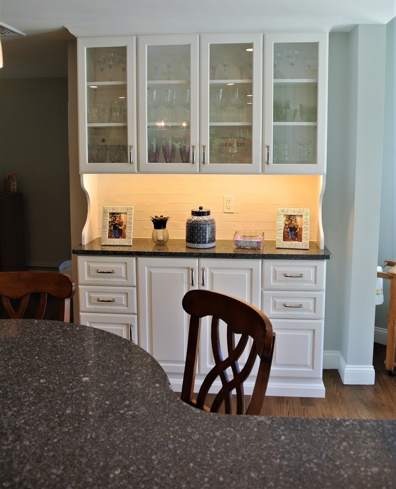 Example of a transitional light wood floor eat-in kitchen design in Boston with an undermount sink, raised-panel cabinets, white cabinets, granite countertops, white backsplash, subway tile backsplash and stainless steel appliances