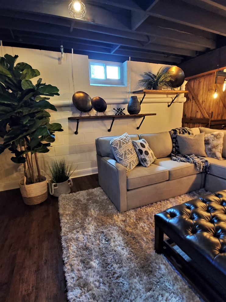This is an example of a medium sized urban fully buried basement in Philadelphia with a home cinema, white walls, laminate floors, a standard fireplace, a wooden fireplace surround, brown floors, exposed beams and feature lighting.