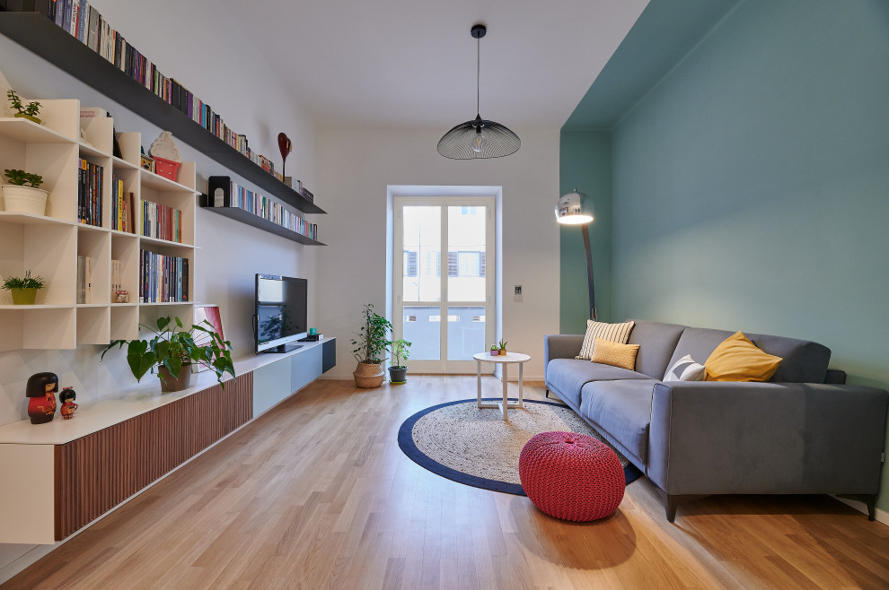 This is an example of a contemporary living room in Rome with blue walls, medium hardwood floors, a wall-mounted tv and brown floor.