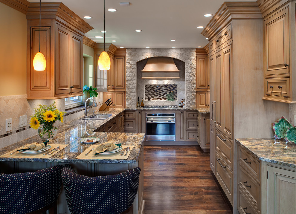 Inspiration for a traditional u-shaped kitchen in Chicago with raised-panel cabinets, light wood cabinets and panelled appliances.