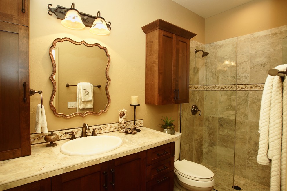 Inspiration for a small mediterranean 3/4 bathroom in Phoenix with a drop-in sink, shaker cabinets, medium wood cabinets, tile benchtops, an alcove shower, beige tile, ceramic tile, beige walls and medium hardwood floors.