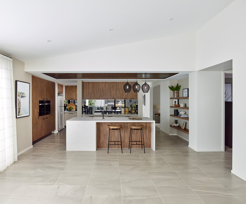 This is an example of a beach style u-shaped open plan kitchen in Other with medium wood cabinets, black splashback, with island, grey floor and white benchtop.