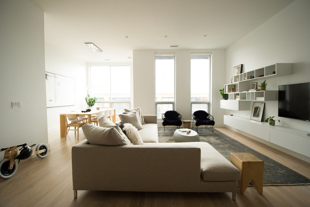 Photo of a scandinavian open concept living room in Chicago with white walls, light hardwood floors, a wall-mounted tv and beige floor.