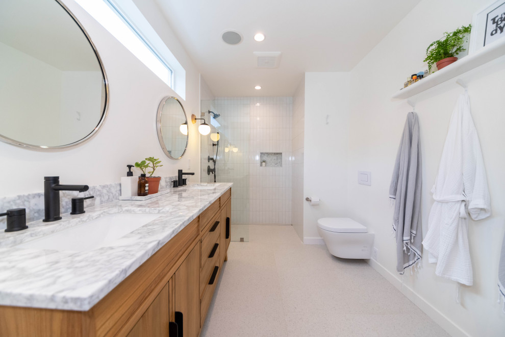 Design ideas for a large modern master bathroom in Los Angeles with furniture-like cabinets, medium wood cabinets, an open shower, a wall-mount toilet, white tile, subway tile, white walls, ceramic floors, an undermount sink, quartzite benchtops, beige floor, a hinged shower door, white benchtops and a double vanity.