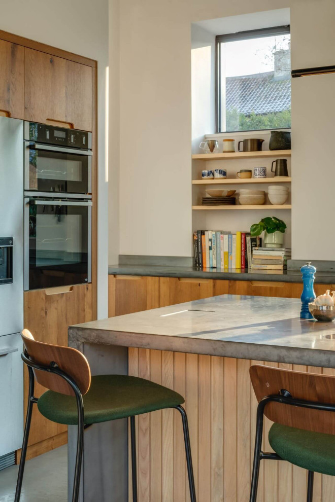 Große Rustikale Wohnküche in L-Form mit flächenbündigen Schrankfronten, hellbraunen Holzschränken, Betonarbeitsplatte, Kücheninsel und grauer Arbeitsplatte in Sonstige