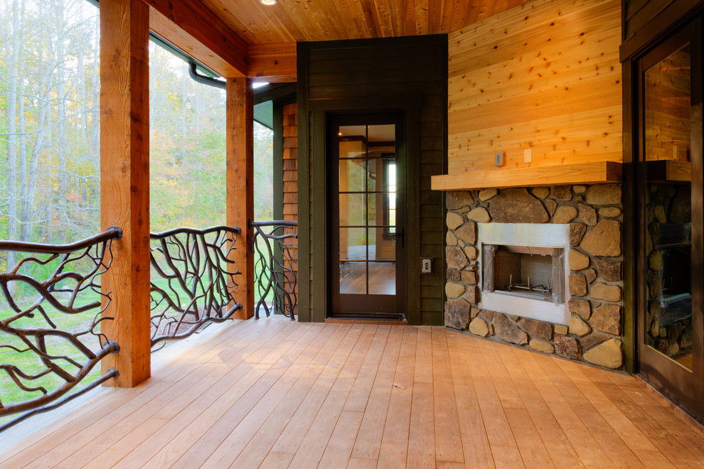 Photo of a mid-sized country backyard deck in Other with a fire feature and a roof extension.